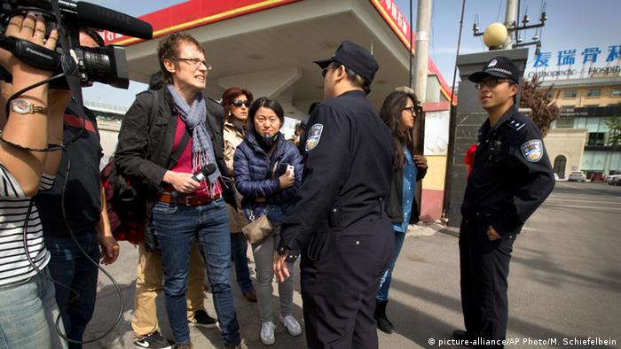 Chinese policemen discuss with a group of journalists
